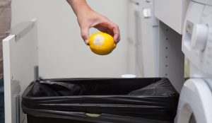 woman putting moldy lemon in the garbage can