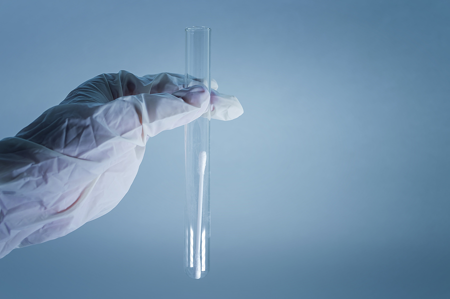 A test tube with a clear liquid in the hand in a medical glove.